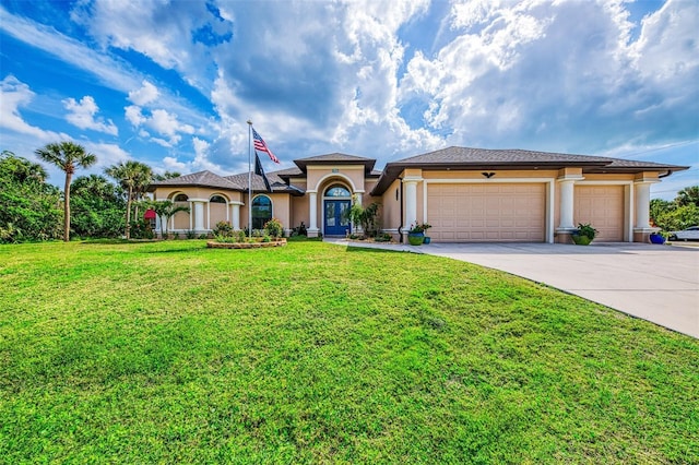 mediterranean / spanish home featuring a garage, a front yard, concrete driveway, and stucco siding