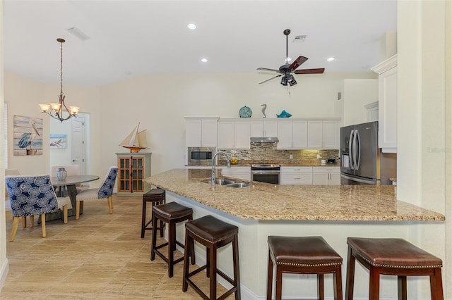 kitchen with stainless steel appliances, tasteful backsplash, visible vents, a sink, and under cabinet range hood