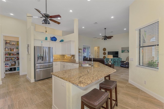 kitchen with open floor plan, a peninsula, white cabinetry, stainless steel refrigerator with ice dispenser, and a sink