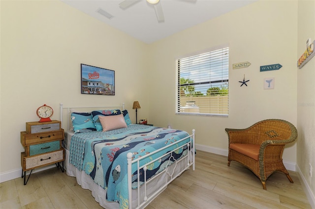 bedroom with a ceiling fan, visible vents, baseboards, and wood finished floors