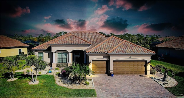 mediterranean / spanish house with stucco siding, a tile roof, an attached garage, decorative driveway, and a front yard