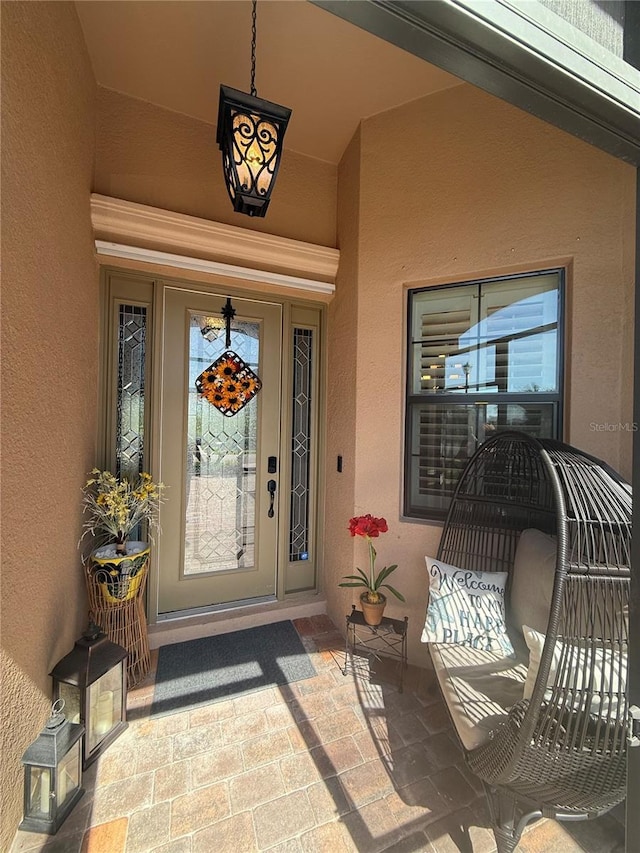 doorway to property featuring a porch and stucco siding