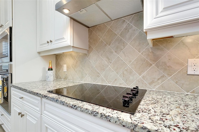 kitchen with light stone counters, stainless steel appliances, backsplash, white cabinets, and exhaust hood