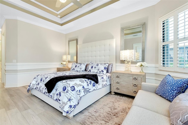 bedroom with light wood finished floors, multiple windows, wainscoting, and crown molding