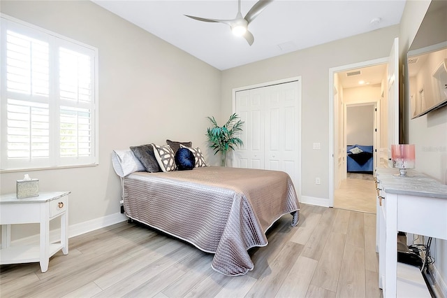 bedroom with visible vents, baseboards, a ceiling fan, light wood-style floors, and a closet