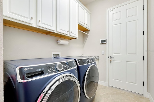 laundry room featuring light tile patterned floors, washer and clothes dryer, cabinet space, and baseboards