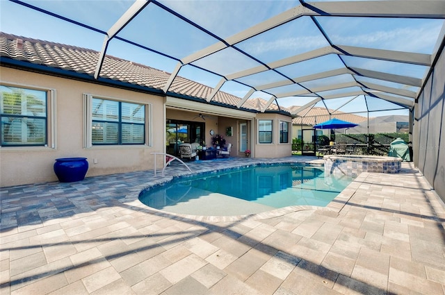 view of pool featuring a ceiling fan, a pool with connected hot tub, a patio, and a lanai