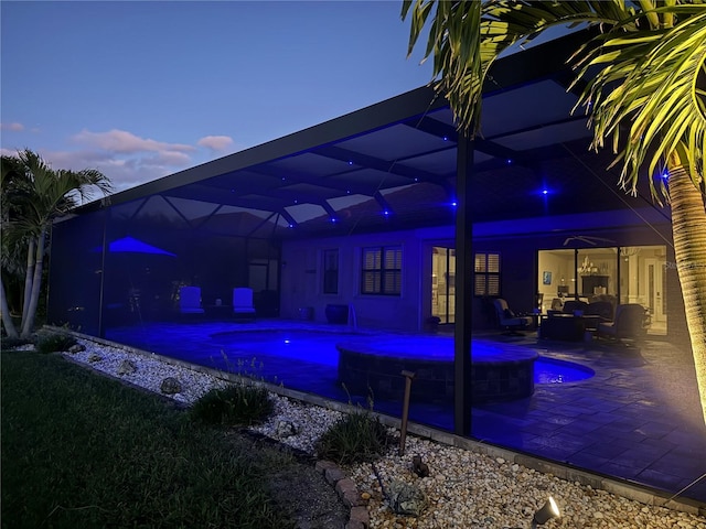 pool at dusk with a lanai, a patio area, an outdoor pool, and outdoor lounge area