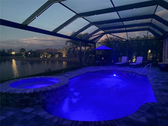 pool at dusk featuring a patio area, glass enclosure, a pool with connected hot tub, and a water view