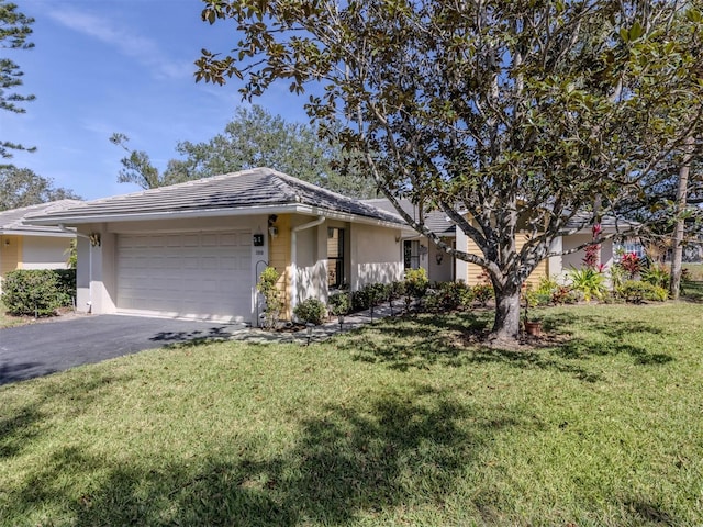 single story home featuring driveway, stucco siding, an attached garage, and a front yard