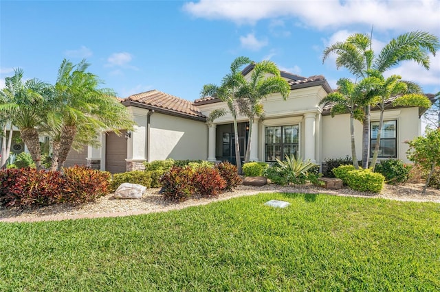 mediterranean / spanish-style house with a garage, stucco siding, a front lawn, and a tiled roof