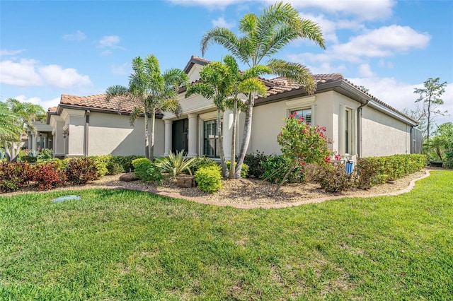 view of front of home with a tile roof, a front lawn, and stucco siding