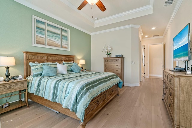 bedroom with visible vents, baseboards, light wood finished floors, a tray ceiling, and crown molding