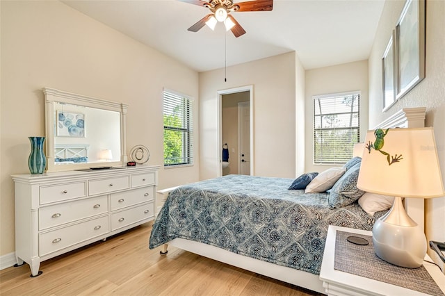 bedroom with light wood-style floors, multiple windows, ceiling fan, and baseboards