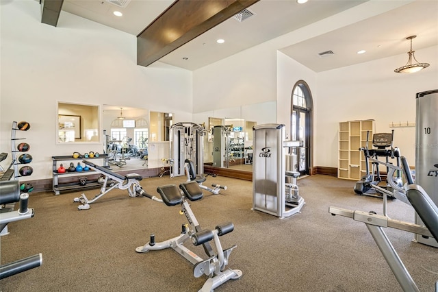 workout area with baseboards, a high ceiling, visible vents, and recessed lighting