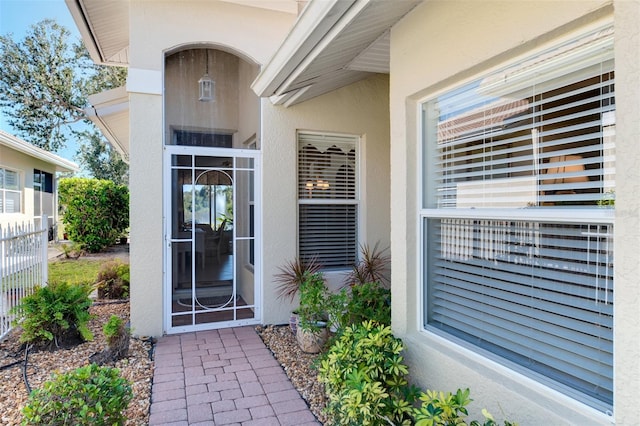 property entrance with stucco siding and fence