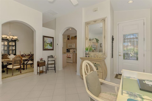 hall featuring a notable chandelier, light tile patterned flooring, and arched walkways