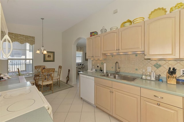 kitchen featuring a sink, white appliances, arched walkways, light tile patterned floors, and decorative backsplash