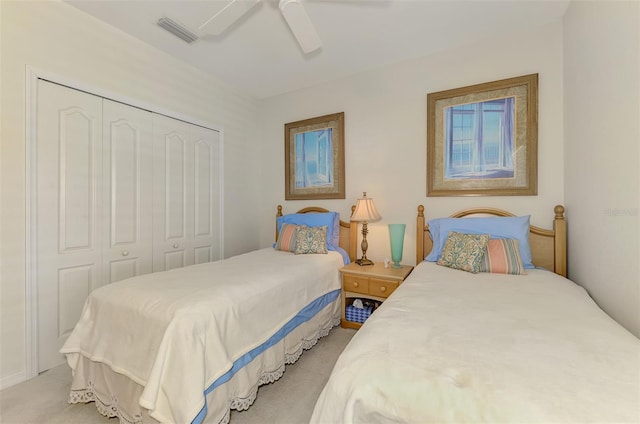 bedroom featuring a ceiling fan, light colored carpet, visible vents, and a closet