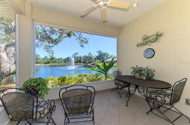 sunroom / solarium with a water view, plenty of natural light, and a ceiling fan