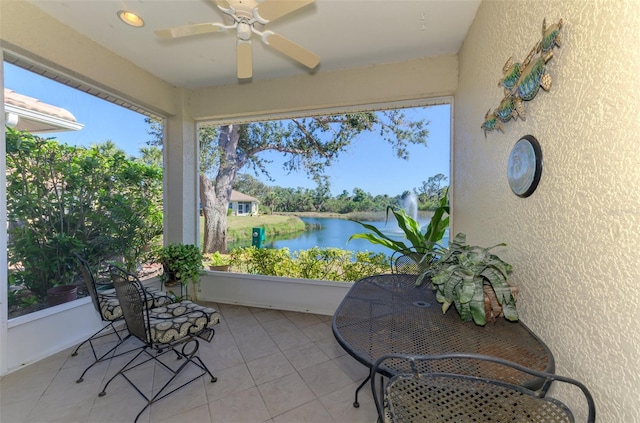 sunroom / solarium featuring a water view and a ceiling fan