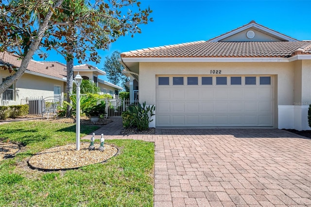 view of front facade featuring stucco siding, decorative driveway, a garage, and a gate