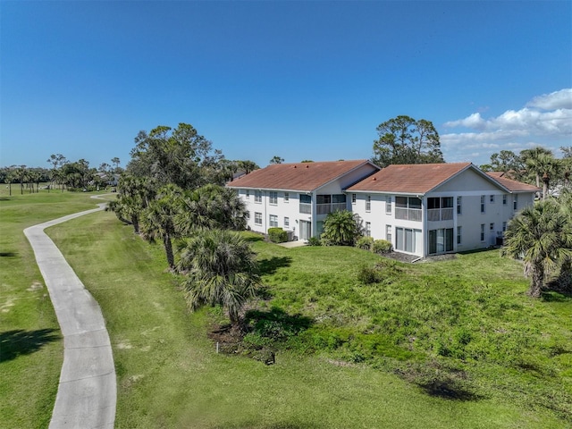 rear view of property featuring a yard and a balcony