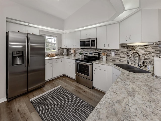 kitchen featuring lofted ceiling, a sink, appliances with stainless steel finishes, tasteful backsplash, and dark wood finished floors