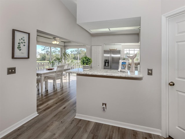 kitchen featuring a healthy amount of sunlight, stainless steel fridge, a peninsula, and white cabinets