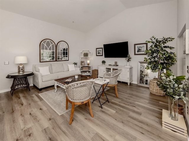 living area featuring lofted ceiling, wood finished floors, and baseboards