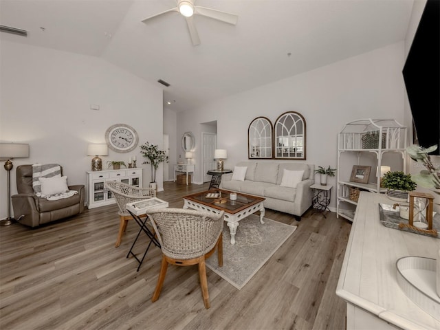 living room featuring lofted ceiling, wood finished floors, and visible vents