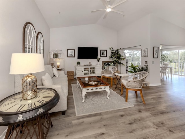 living area featuring a healthy amount of sunlight, high vaulted ceiling, a ceiling fan, and wood finished floors