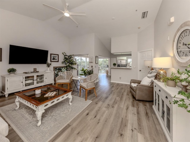 living area featuring baseboards, high vaulted ceiling, a ceiling fan, and light wood-style floors