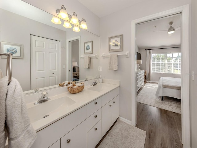 ensuite bathroom with double vanity, ensuite bath, a sink, and wood finished floors