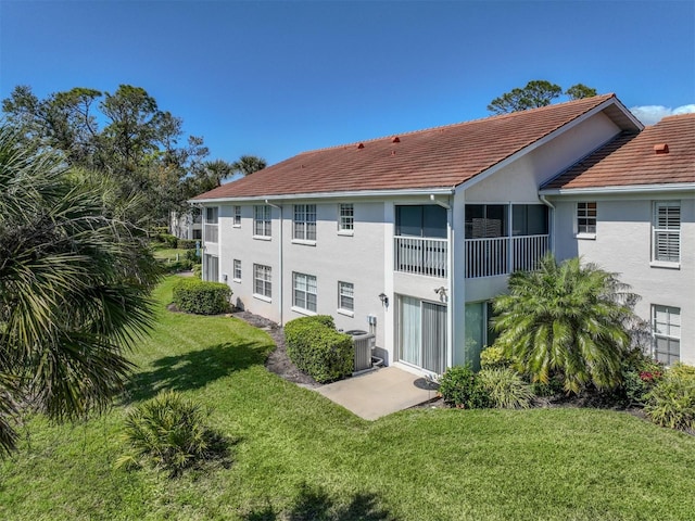 rear view of property with stucco siding, a yard, and central air condition unit