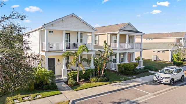 multi unit property with covered porch, a front yard, and a balcony