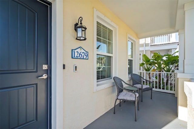 view of exterior entry featuring a porch and stucco siding