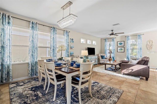 dining space featuring ceiling fan with notable chandelier, light tile patterned flooring, visible vents, and baseboards