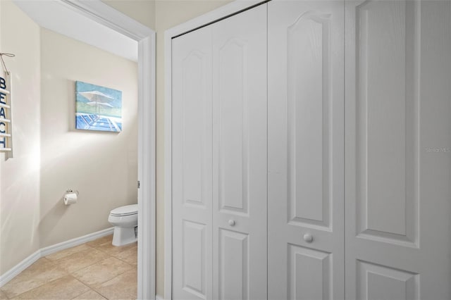 bathroom with tile patterned flooring, a closet, baseboards, and toilet