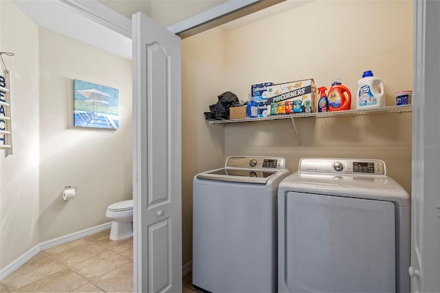 laundry area with washer and dryer, laundry area, light tile patterned flooring, and baseboards