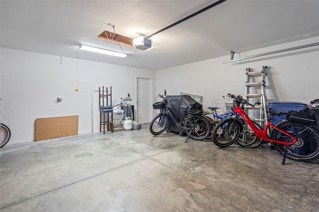 garage with concrete block wall, bike storage, and a garage door opener