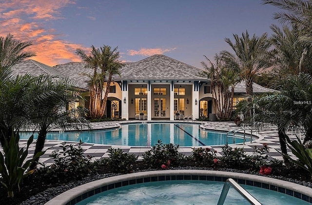 view of swimming pool with a patio area, a community hot tub, french doors, and an outdoor structure