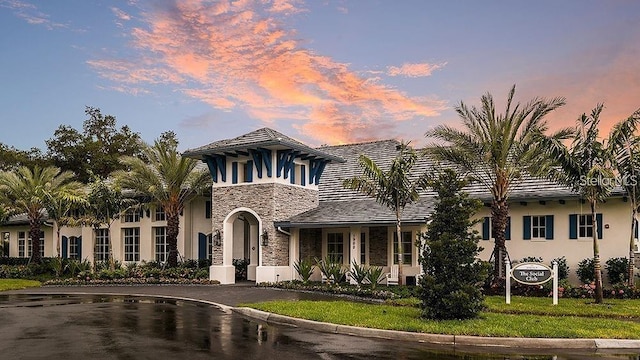 view of front of house with stone siding, a front yard, and stucco siding