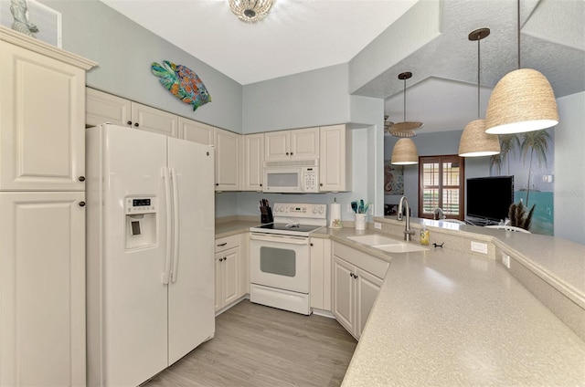 kitchen featuring pendant lighting, light countertops, light wood-style floors, a sink, and white appliances