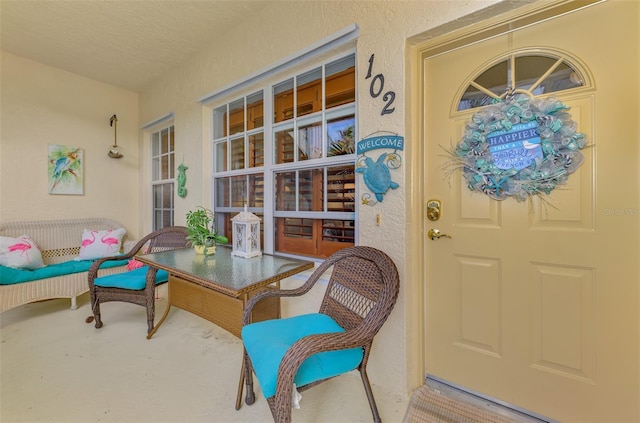 view of exterior entry featuring a porch and stucco siding