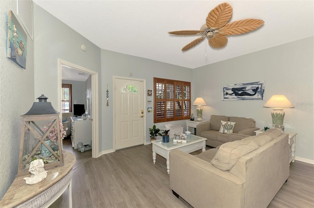 living room featuring a ceiling fan, light wood-style flooring, and baseboards