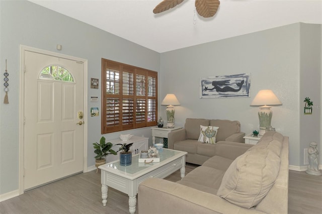 living area featuring ceiling fan, baseboards, and wood finished floors