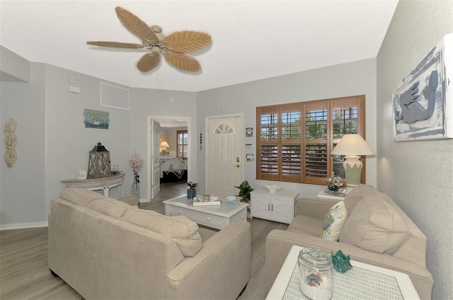 living area with light wood-style flooring, baseboards, ceiling fan, and a wealth of natural light