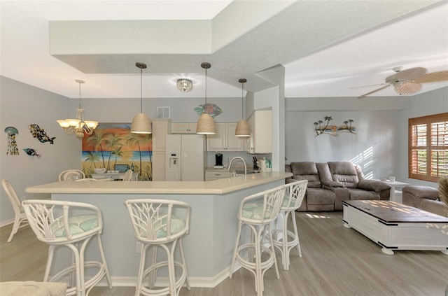 kitchen featuring a breakfast bar, white refrigerator with ice dispenser, light wood finished floors, light countertops, and open floor plan