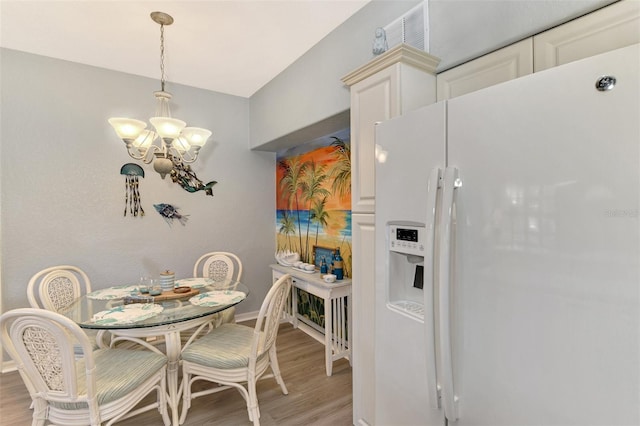 dining area featuring baseboards, a notable chandelier, and light wood finished floors